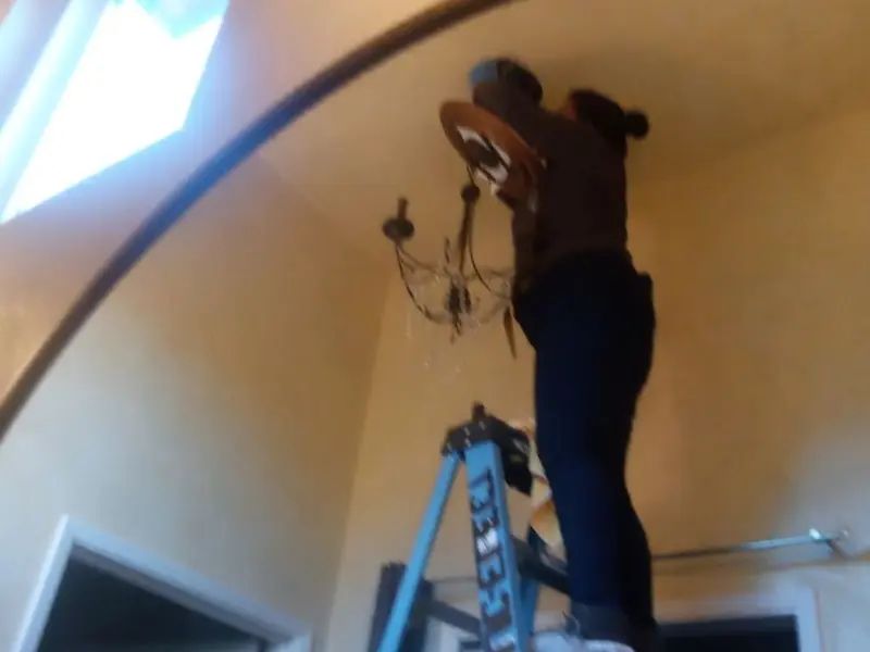 Electrician installing a chandelier in a Seminole residence